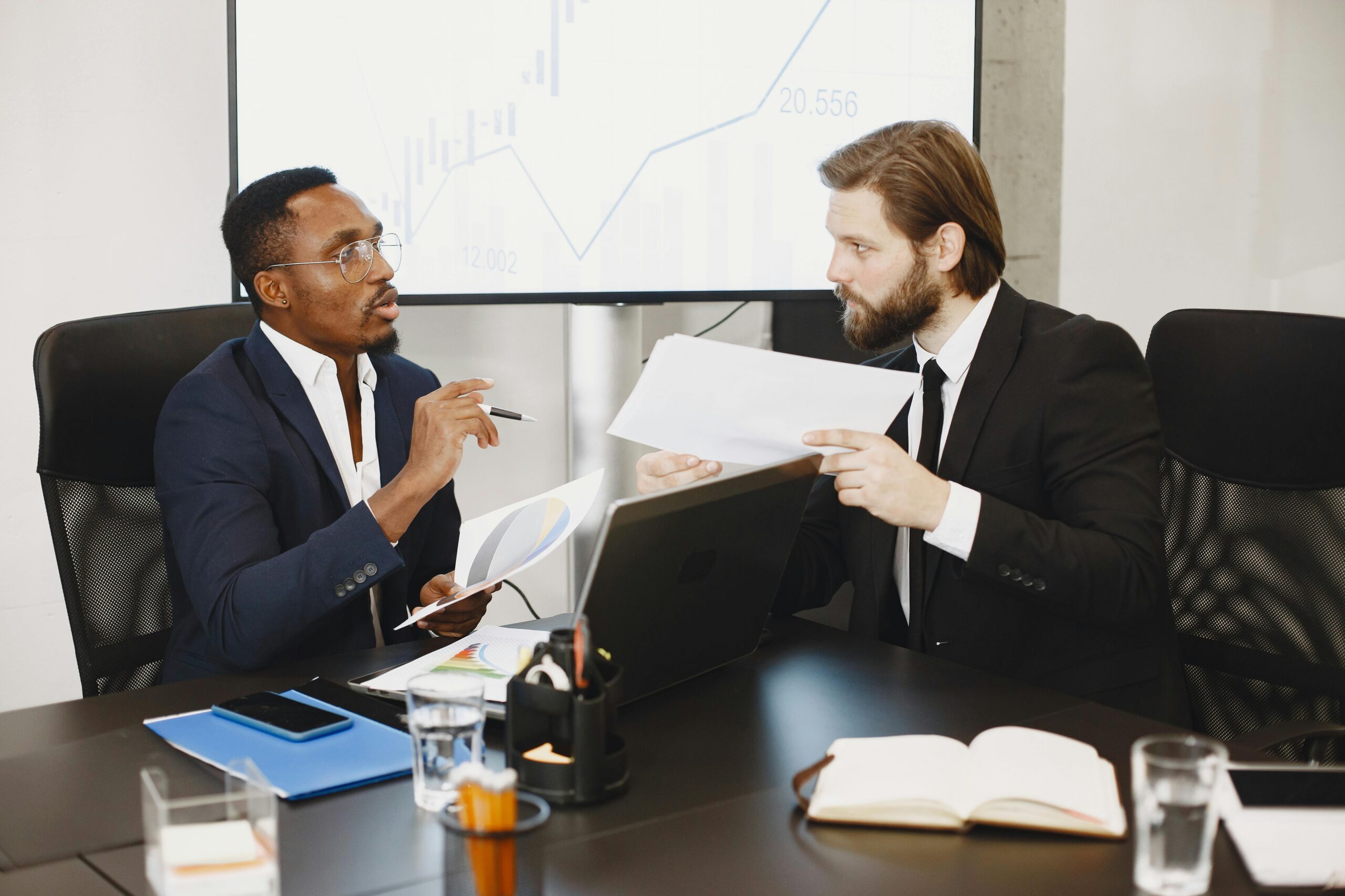Two business professionals engaged in a planning meeting, discussing documents in a modern office setting.